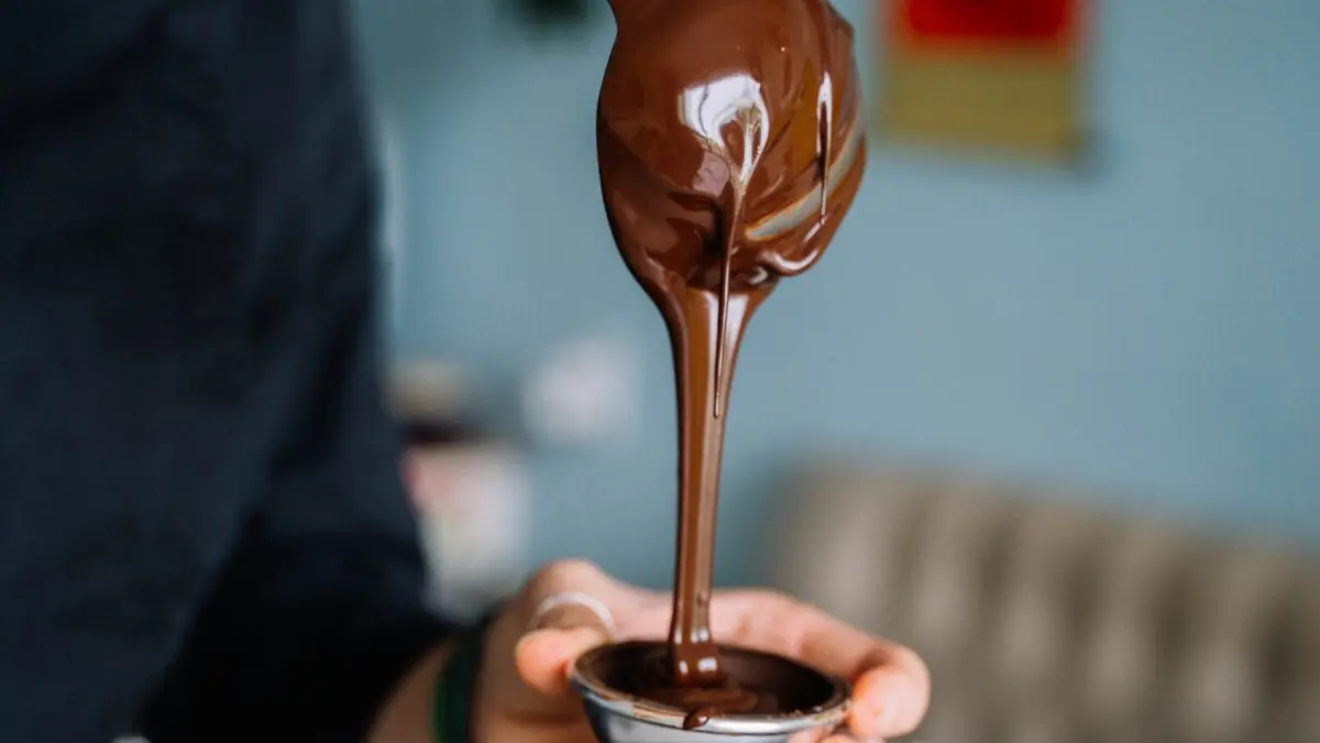 Concha derramando calda de chocolate em potinho de vidro