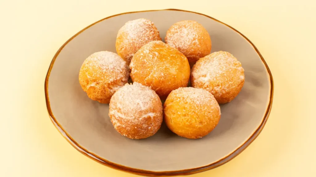 7 unidades de bolinho de chuva em prato de cerâmica com açúcar polvilhado