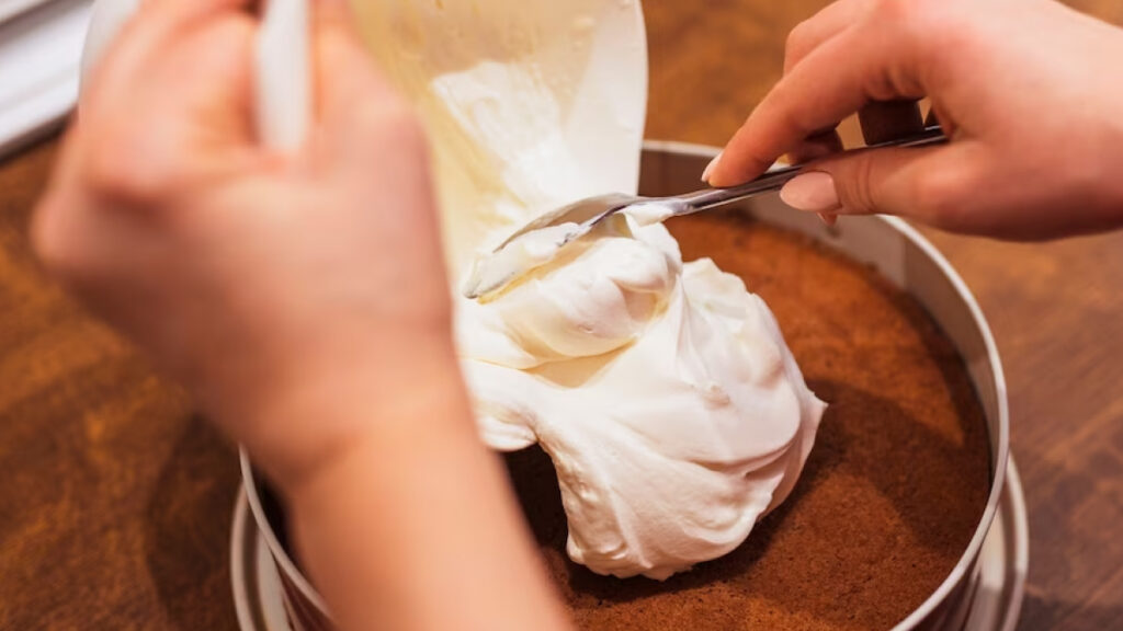 Chantilly sendo colocado em cima de um bolo