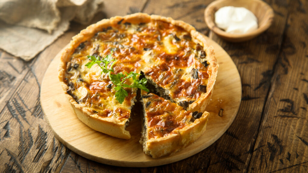 Quiche servida em uma tábua redonda de madeira