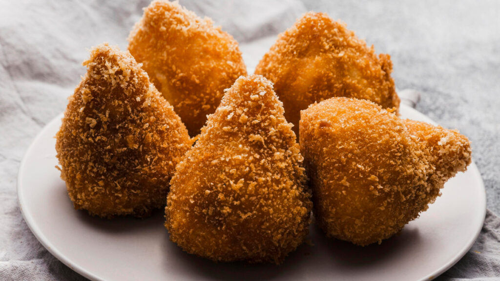 5 unidades de coxinha de batata doce vistas de perto em prato branco