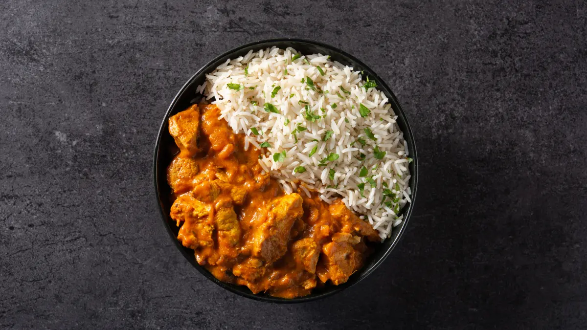 Frango ao curry servido com arroz branco em bowl preto
