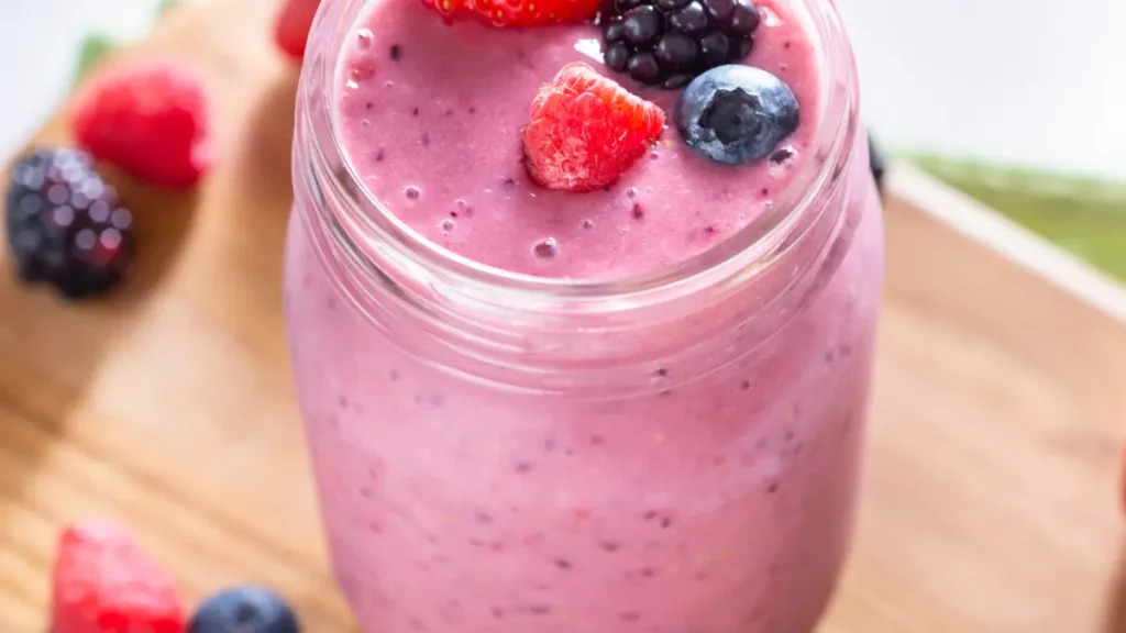 Smoothie de frutas vermelhas em jarra de vidro com frutas vermelhas frescas em cima