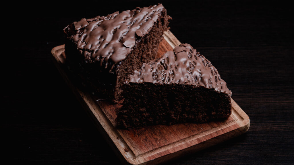 Duas fatias triangulares de Bolo de chocolate de liquidificador servidas em uma tábua de madeira