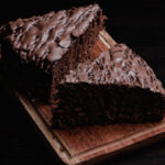Duas fatias triangulares de Bolo de chocolate de liquidificador servidas em uma tábua de madeira