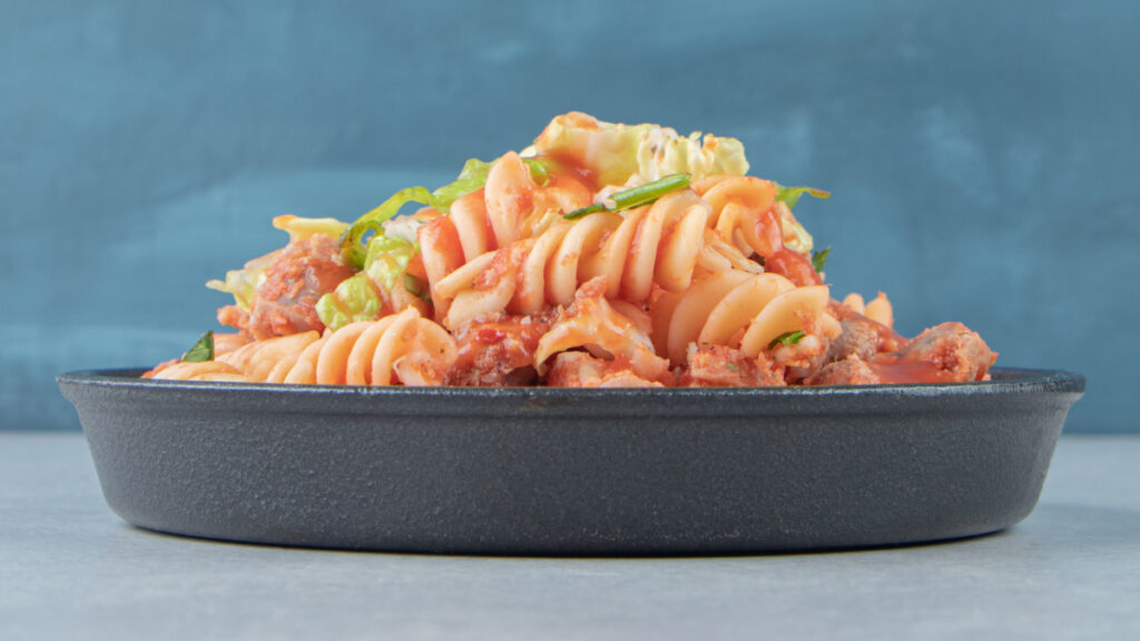 Macarrão de forno em travessa preta vista de lado