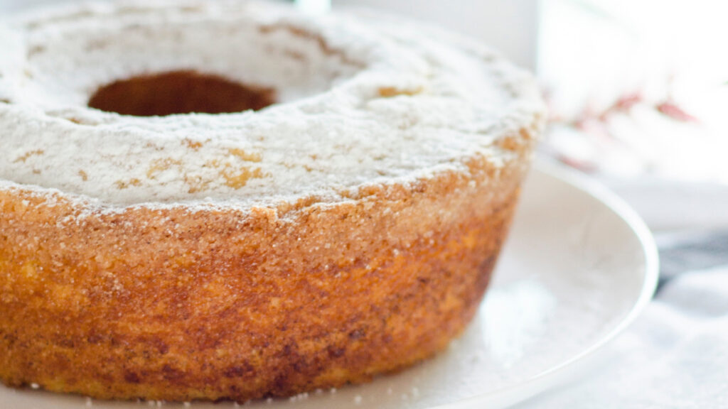 Bolo de baunilha polvilhado com açúcar de confeiteiro em prato branco