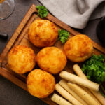 5 unidades de bolinho de bacalhau visto de cima em tábua de madeira