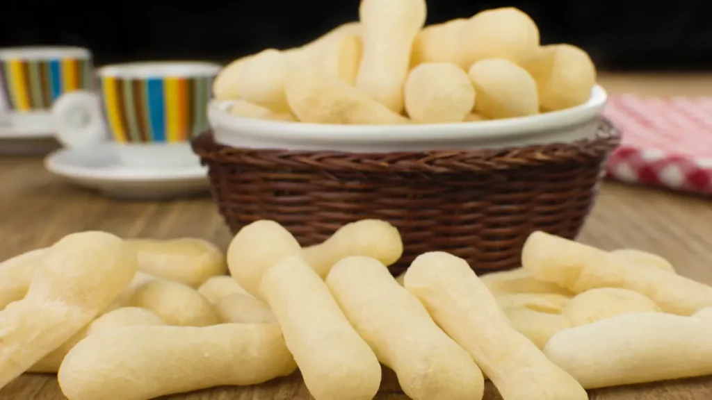 Biscoito de polvilho servido em cesta trançada e alguns polvinhos na mesa