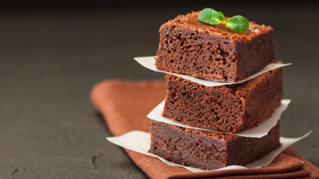 3 unidades de brownie sem glúten e sem lactose em cima do outro separados por pedaço de papel