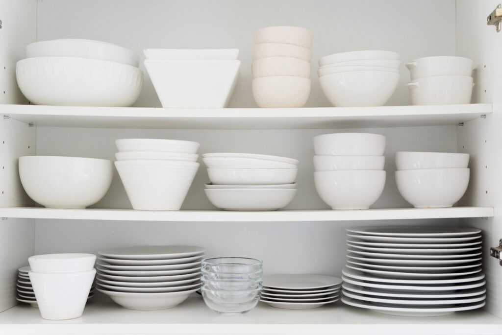 Pratos e bowls organizados por tipo e tamanho dentro de um armário