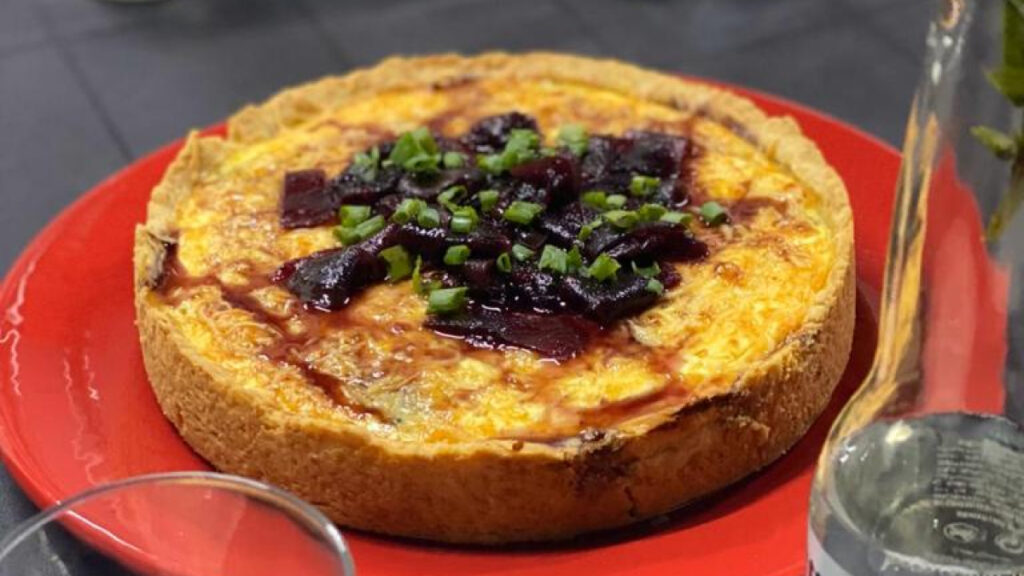 Quiche de gorgonzola com pera reduzida no vinho servida em prato vermelho