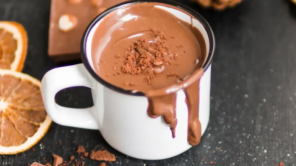 Chocolate quente simples derramando em xícara de alumínio branca com borda preta