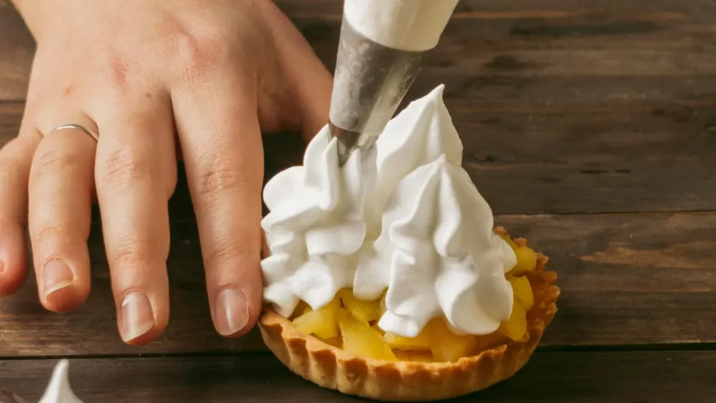 Merengue suíço sendo colocado em tortinha