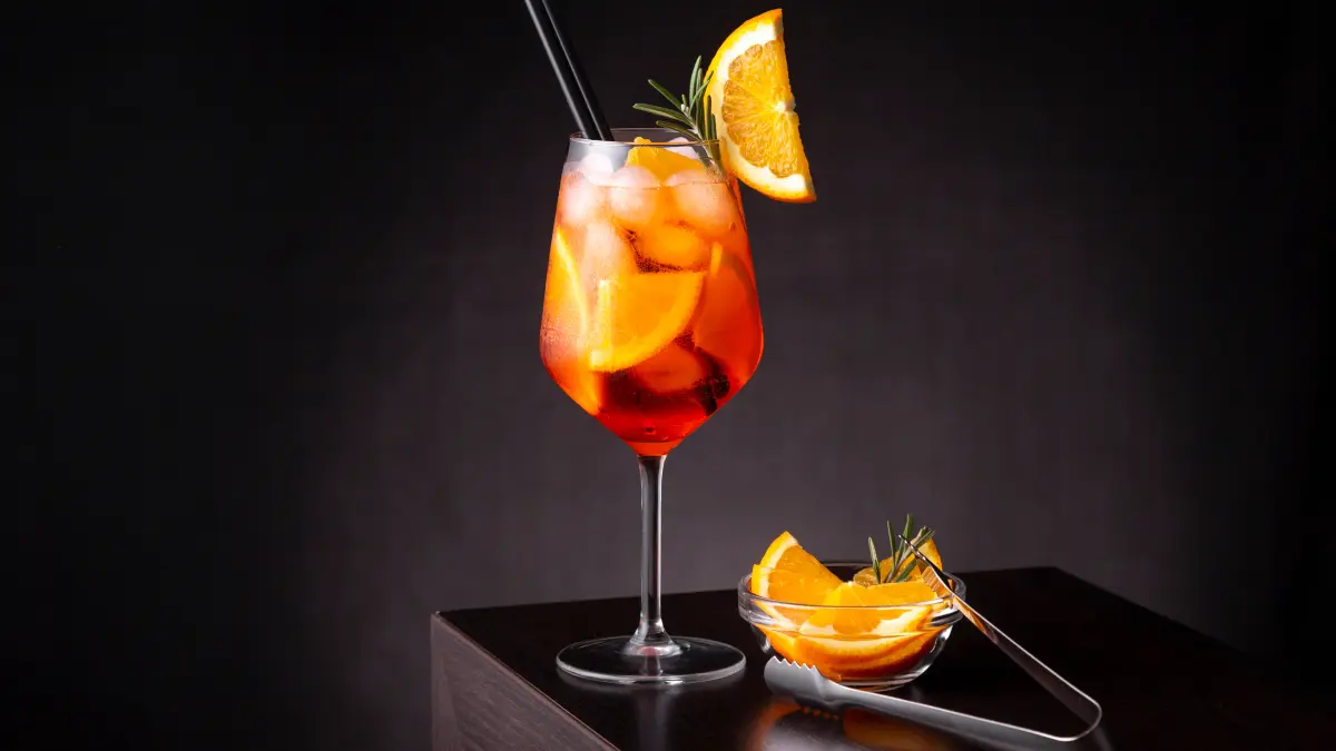 Drink aperol em taça de vidro com um pedaço de laranja na borda da taça