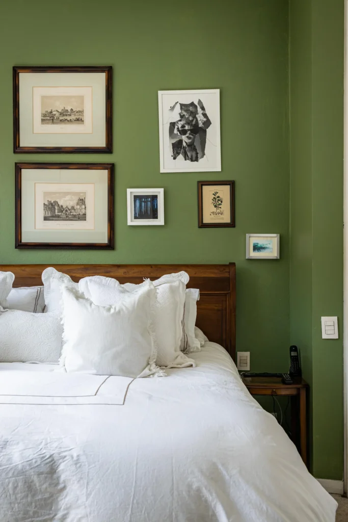 Quarto com parede verde, quadros e cabeceira rustica