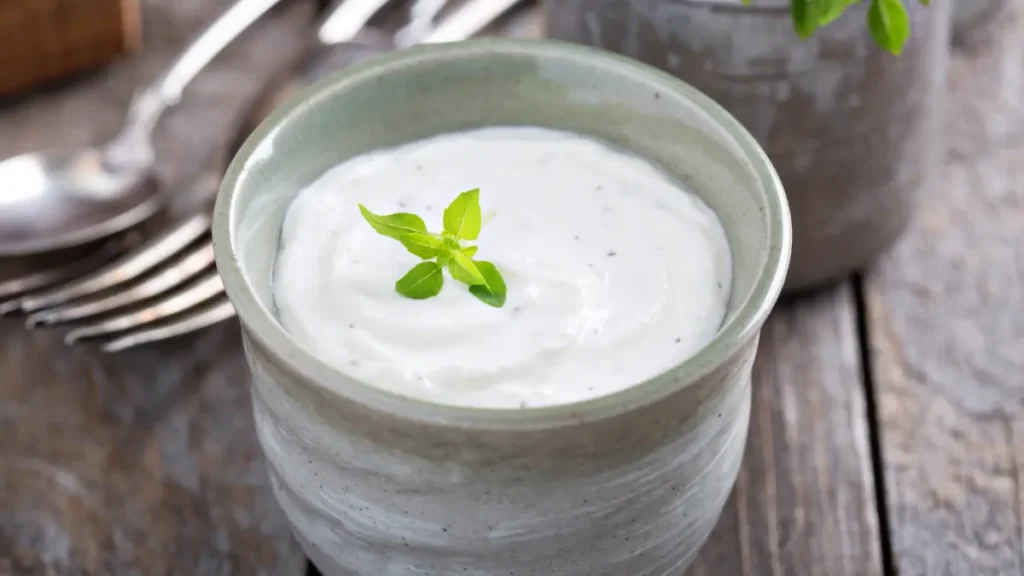 Sour cream servido em recipiente de cerâmica cinza e finalizado com folha de hortelã