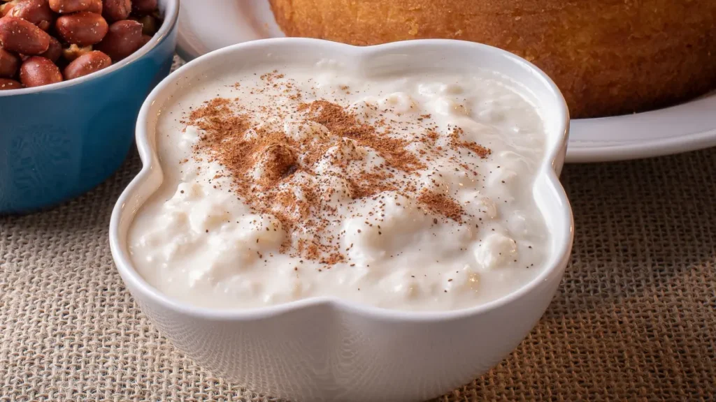 Canjica de milho branco servido em recipiente de vidro branco com canela salpicada por cima