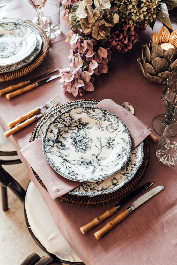 Pratos estampados, guardanapos, talheres e flores para decorar a mesa