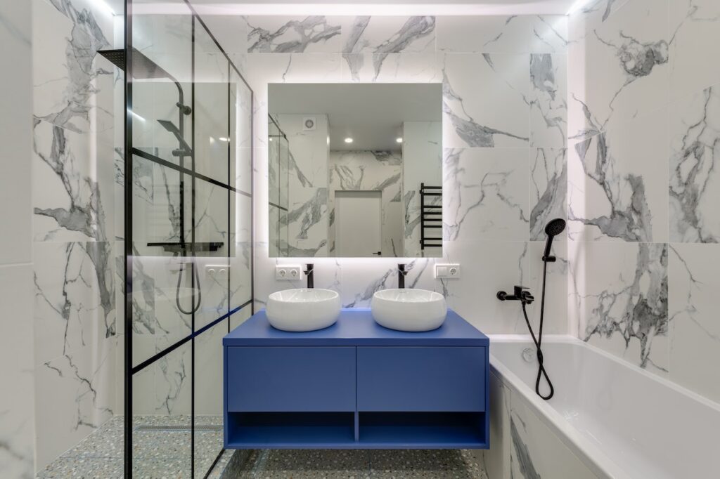 Banheiro com bancada, armários azuis e cubas