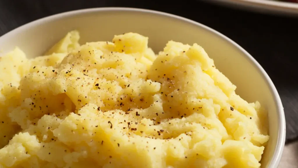 Pure de batata doce em bowl branco com uma pitada de pimenta do reino