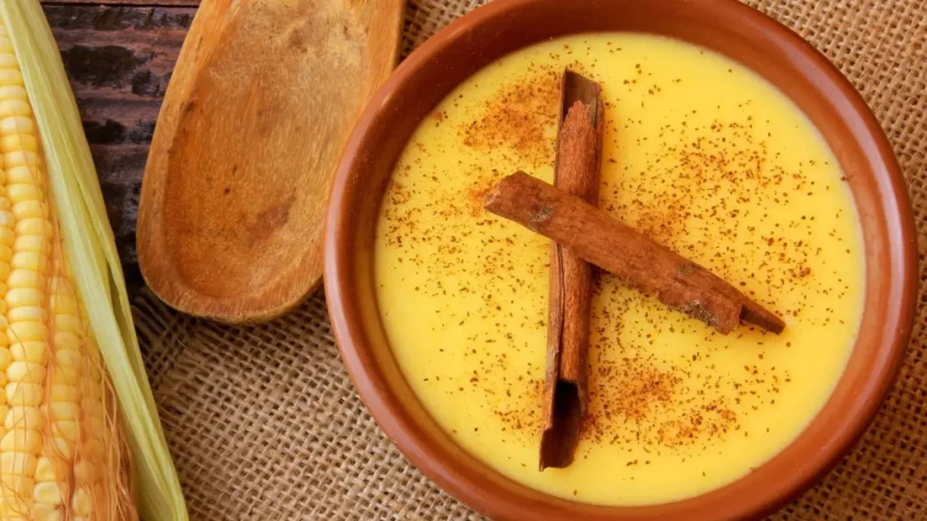 Curau de milho em bowl de cerâmica com canela em pó e pau de canela vista de cima