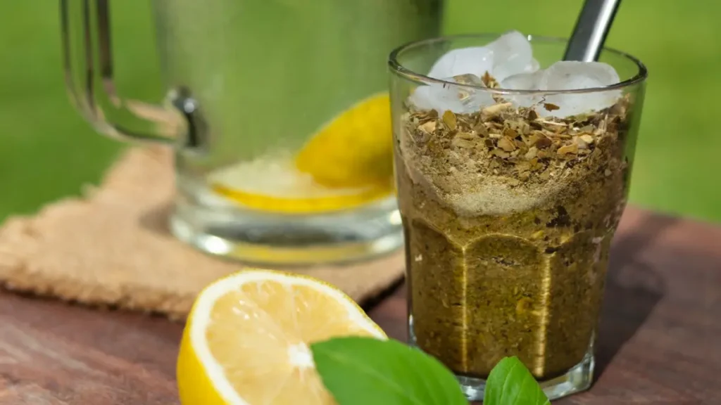 Tereré com pedras de gelo em copo de vidro em cima de mesa de madeira