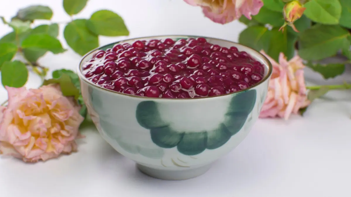Sagu de vinho servido em bowl de porcenala com flores ao fundo