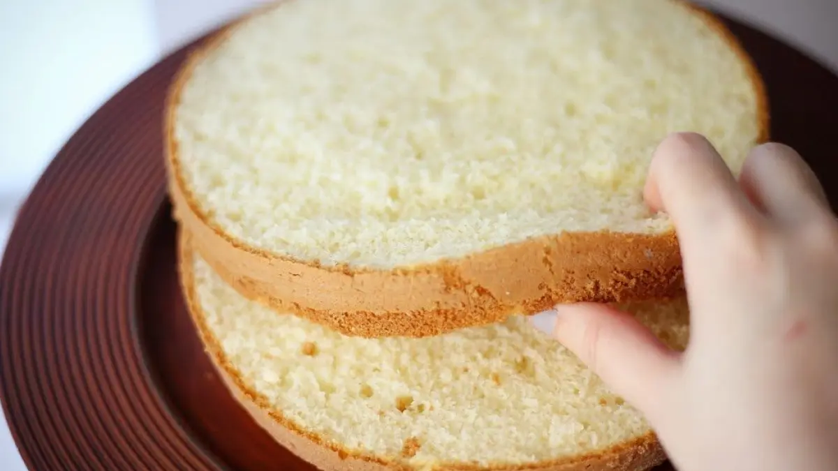 Mão abrindo massa de bolo de pão de ló