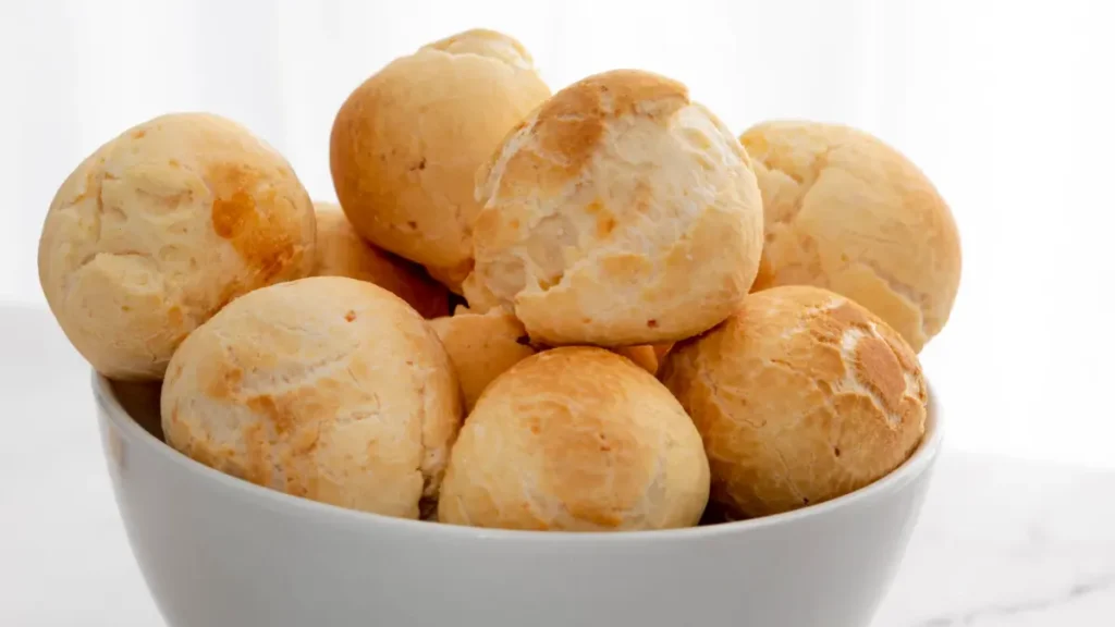 Pães de queijo distribuídos em uma tigela branco.