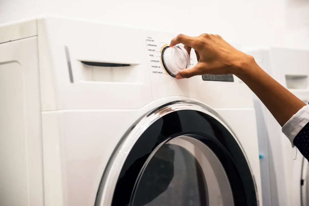 Pessoa ajustando a função da máquina de lavar roupas em botão de acionamento