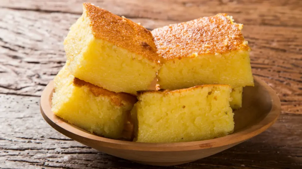 Fatias de pamonha de forno em cima de prato de madeira