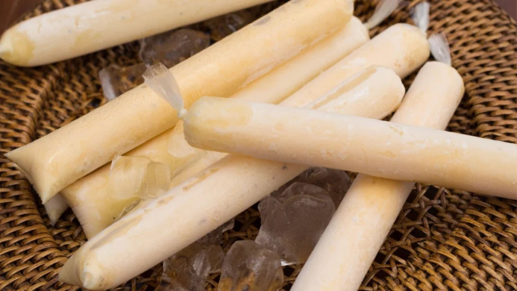 Geladinhos de coco em saquinhos com fundo de madeira marrom.