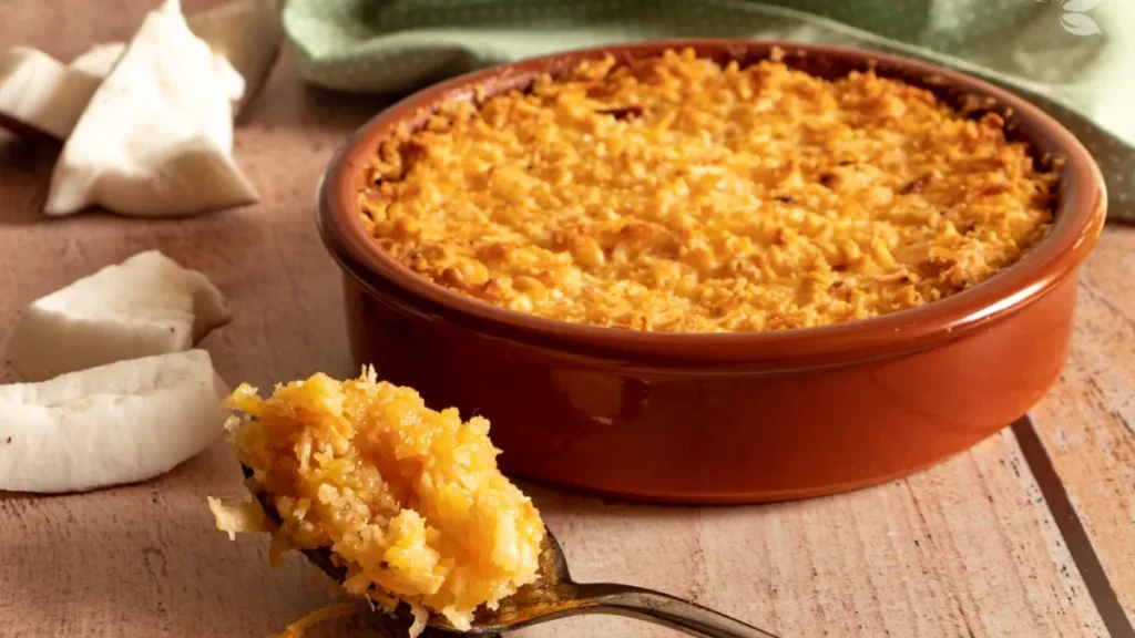 Cocada de forno em panela marrom com uma pedaço na colher.