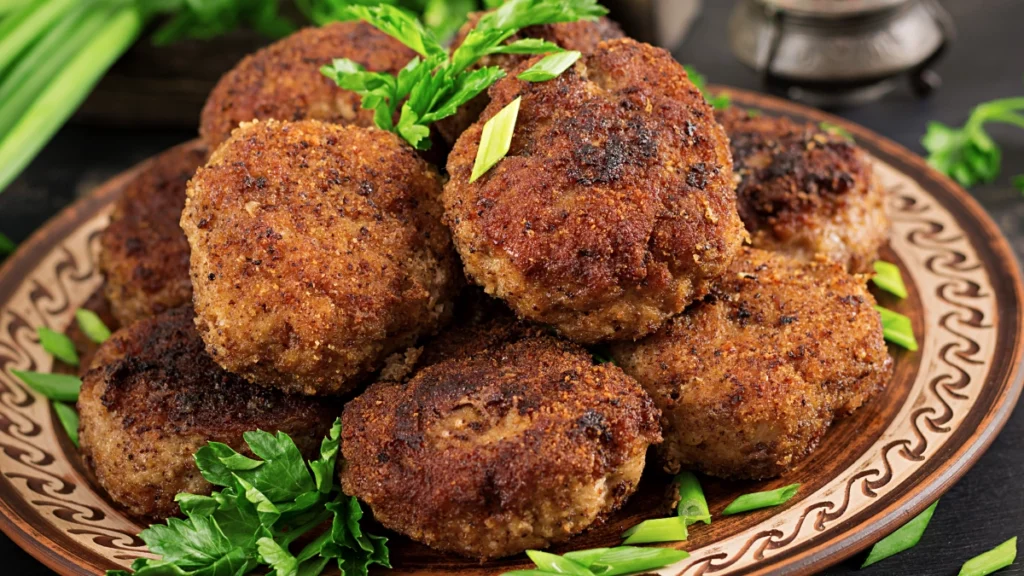 Bolinhos de carne moída em uma tigela marrom com algumas folhinhas de decoração.