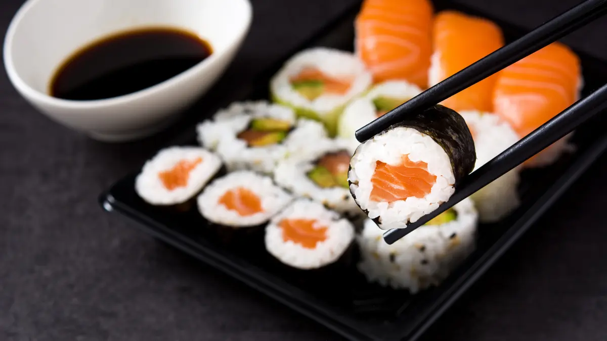Pauzinhos segurando um sushi para contar a história do sushi