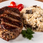 Risoto de carne com decoração ao lado em prato branco.