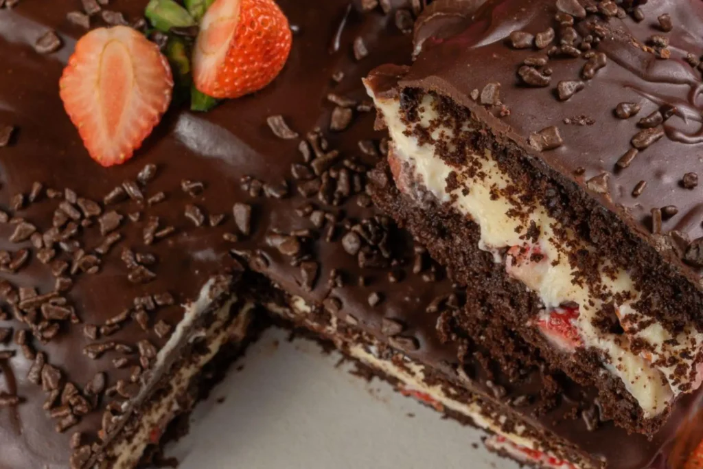 Bolo de chocolate com recheio de coco e morango, cobertura de chocolate e morangos por cima