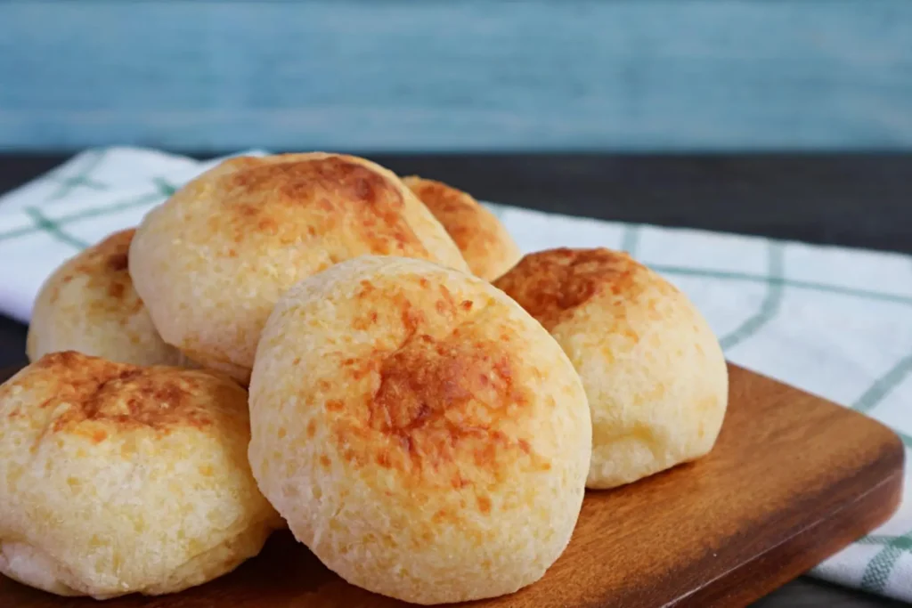 Pães de queijo em cima de uma tábua de madeira.