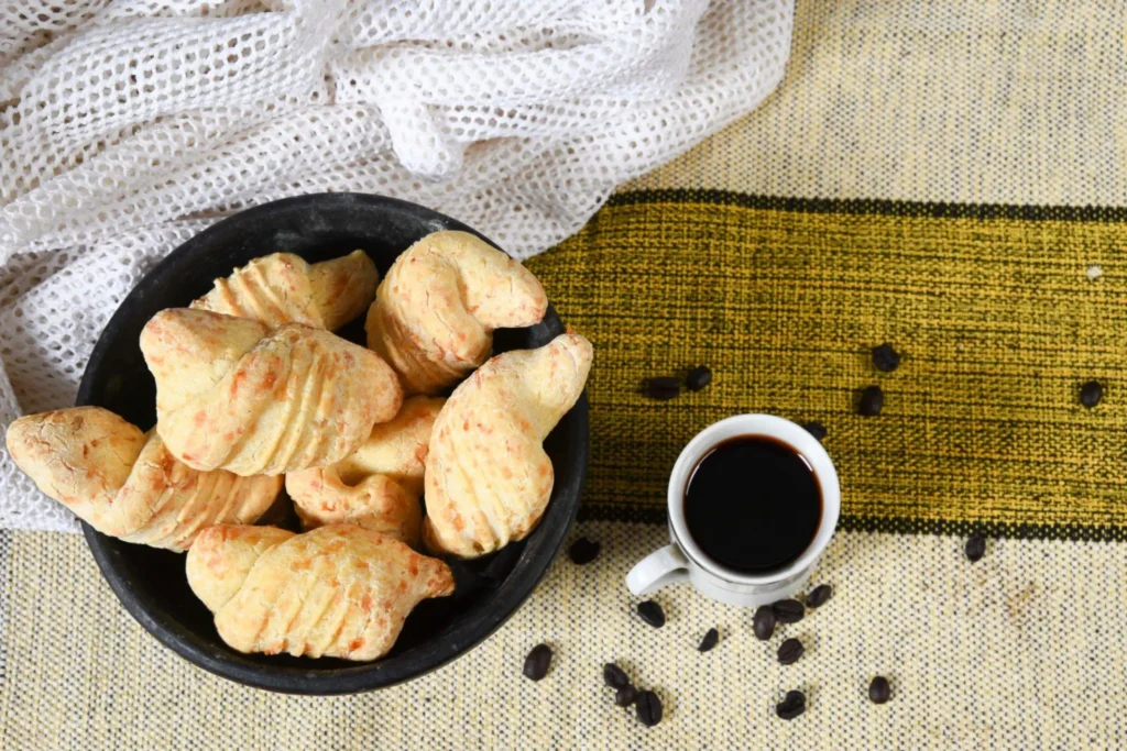 uma vasilha com biscoito de queijo e um café ao lado