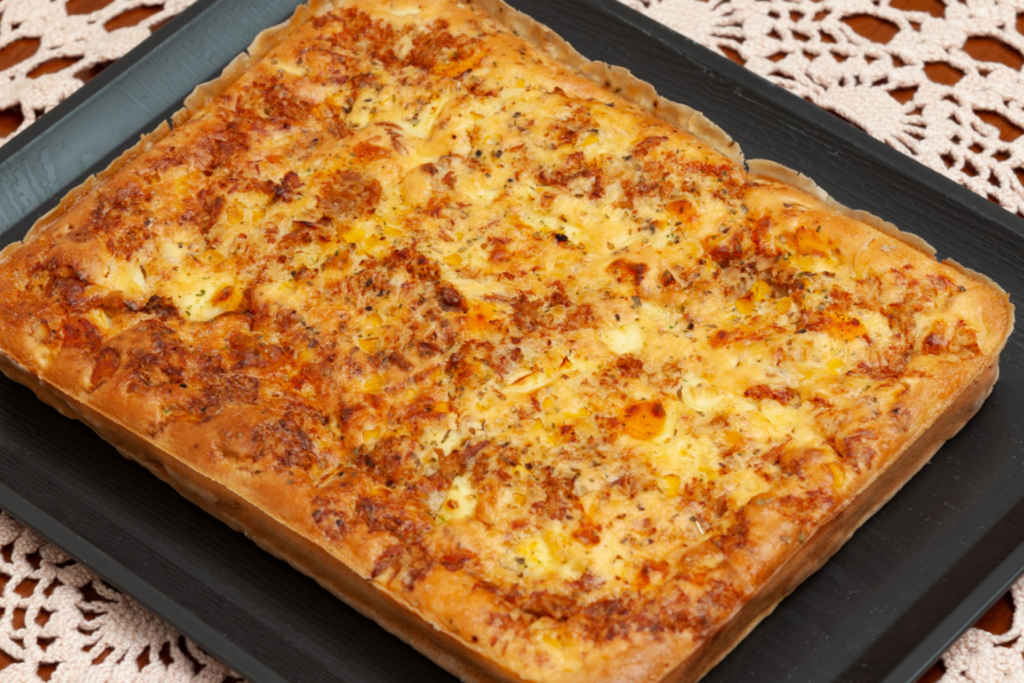 Torta de calabresa feita no liquidificador servida em travessa de cor preta sobre uma mesa com toalha de croche