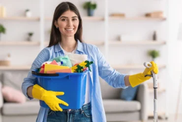 Mulher com acessórios e materiais de limpeza na mão pra fazer a higienização da sua casa