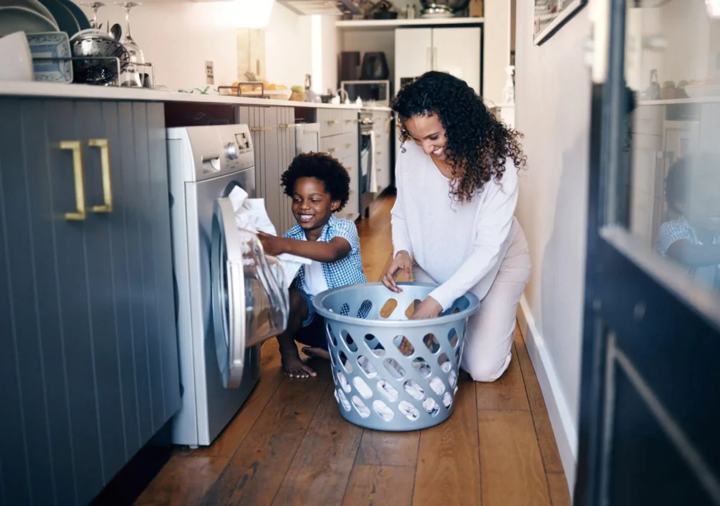 Mãe e filho higienizando as roupas em máquina de lavar
