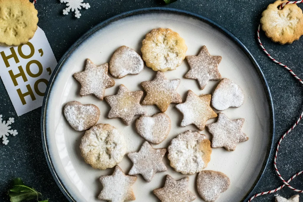 Biscoito de gengibre servido em prato branco com enfeites natalinos ao redor.