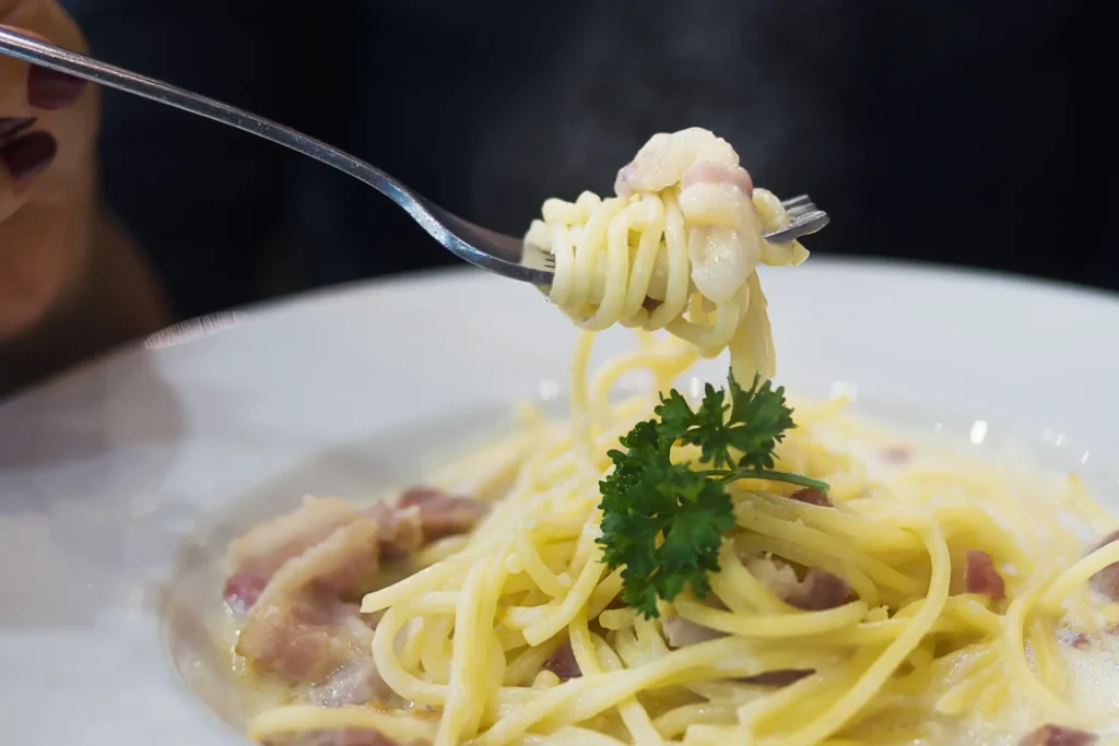 Molho carbonara em macarrão enrolado no garfo.