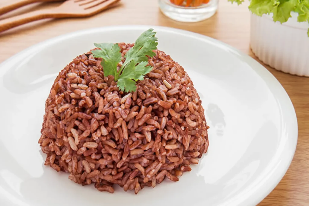 Arroz vermelho cremoso servido em prato de louça branco