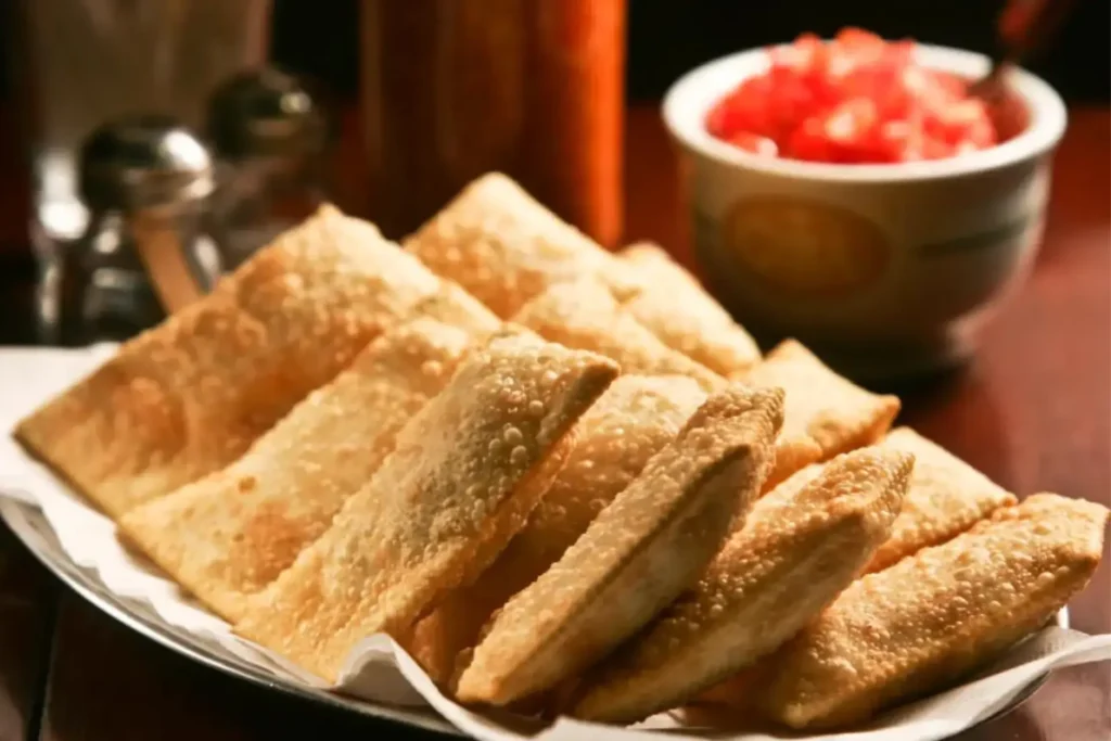 Pastelzinho de boteco servido com salada de tomate.