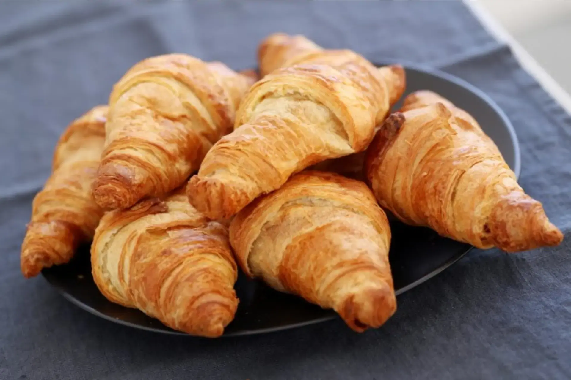 Croissant servido em prato preto.